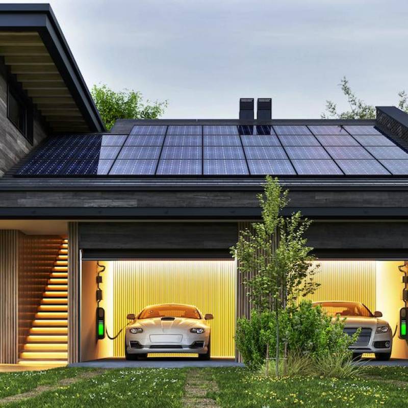 Evening view of a modern house with solar panels and electric cars Evening view of a modern house with solar panels and electric cars